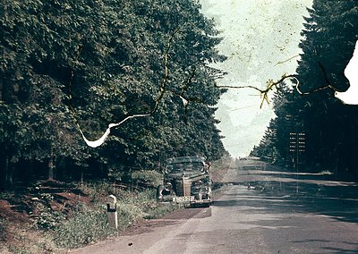 Vintage sepia-toned photo of a mid-20th-century roadside scene, featuring a classic sedan parked beside a mailbox. Dense ever...