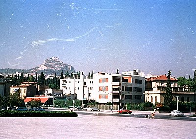 Mid-20th century urban scene with Soviet-era apartment blocks, flat roofs, and minimalist architecture. Prominent hilltop for...