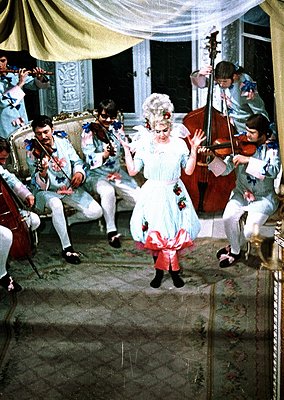 Vintage 19th-century indoor musical performance with classical string ensemble. Central figure in elaborate white gown with r...