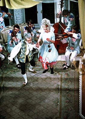 Vintage indoor dance scene with 19th-century-inspired costumes: men in striped pants with vests, women in puff-sleeve dresses...