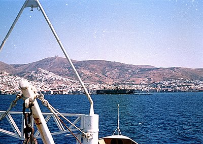 Vintage seascape shot from a boat’s rail, showing a coastal town nestled between hills and deep blue waters. Mid-20th century...