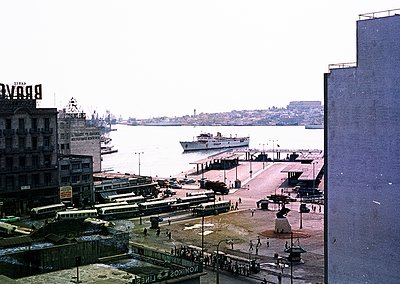 Vintage seaside port scene with Soviet-era ferry docked, likely , Bulgaria, mid-20th century. Prominent Cyrillic signage ("ДЕ...