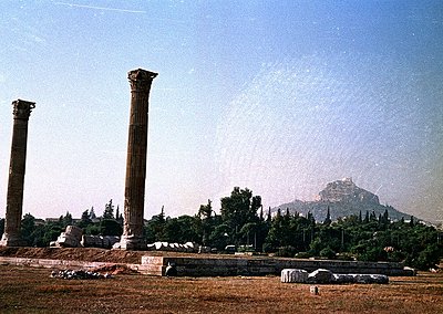 Ancient Greek-style columns and ruins in a sunlit archaeological site, likely the Temple of Dionysus in Athens. Fluted Doric ...