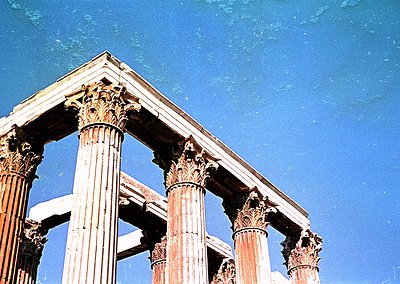 Ancient Corinthian columns under clear blue sky, showcasing intricate acanthus leaf capitals. Likely part of a Roman or Greek...