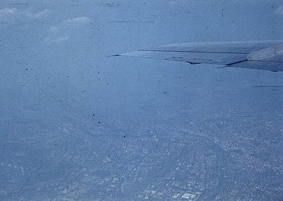 Aerial view of a snow-covered landscape with subtle urban grid patterns beneath. Likely a cityscape obscured by winter snowfa...