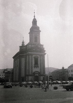 Neoclassical church with twin towers and central spire, likely Eastern European. Symmetrical facade with arched windows and a...