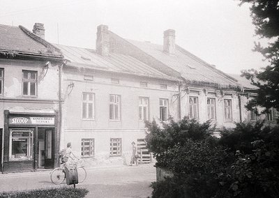 Two-story Soviet-era brick building with symmetrical white-framed windows, likely a commercial/residential hybrid. Signage re...