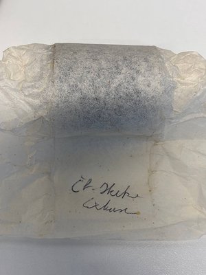 Vintage paper wrapping with handwritten Cyrillic inscription "Ел. Дике" and "Експо" on a rectangular stone block, likely a de...