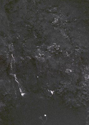 High-contrast aerial nighttime shot of urban sprawl, likely from satellite or drone. Distinctive bright city lights outline a...