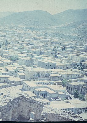 Aerial view of a densely packed, historic urban landscape with flat-roofed buildings and narrow streets, likely Mediterranean...