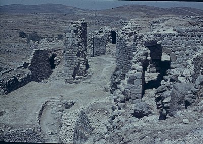Ancient stone ruins in arid landscape, featuring partial walls and doorways. Likely Byzantine or early medieval fortress rema...