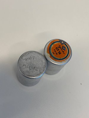 Vintage metal film canisters with handwritten markings and "UTI6" branding. Left canister shows faded Cyrillic text and seria...
