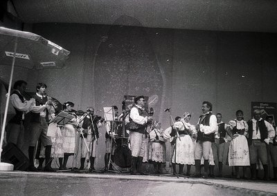 Traditional folk ensemble performing on stage, likely Eastern European, mid-20th century. Instruments include accordions, vio...