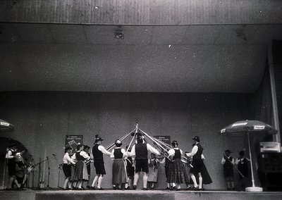 Vintage black-and-white photo of a traditional folk dance performance, likely Eastern European. Group of dancers in coordinat...
