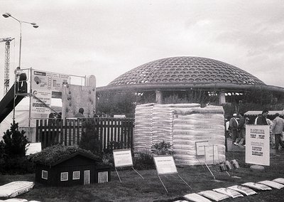 Mid-century futuristic pavilion with honeycomb dome structure, likely from a 1960s–1970s world’s fair or expo. Surrounding di...