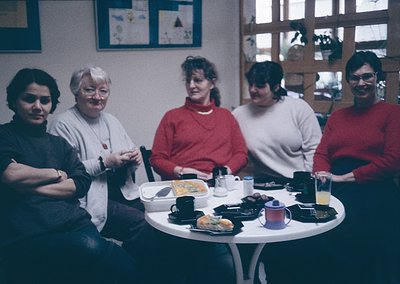 Vintage group portrait of five individuals seated around a round table in a cozy indoor setting, likely a 1980s-1990s home or...
