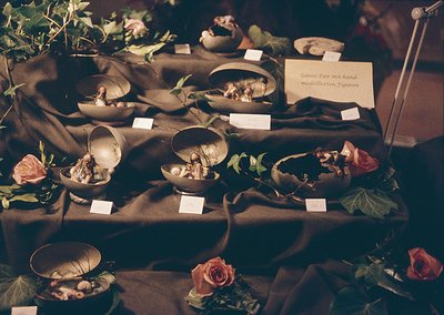 Vintage ceramic goose figurines with hand-modeled features displayed on a draped table, surrounded by artificial foliage and ...