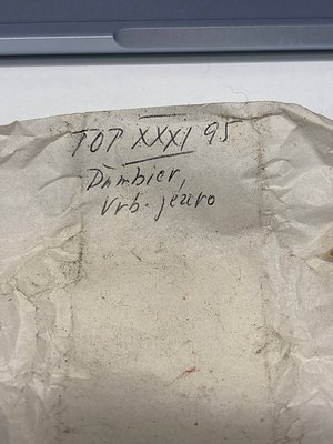 Close-up of a concrete slab with handwritten markings: "TOP XXXI 95" and "Dambier / Urb. Jero." on weathered surface. Likely ...
