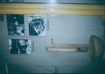 Vintage wooden megaphone mounted on a wall with three black-and-white aerial photographs in frames. Likely from mid-20th cent...