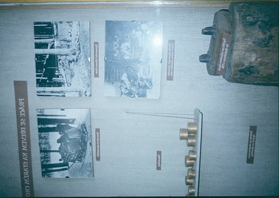 Historic WWII exhibit panel featuring sepia-toned black-and-white photos of wartime scenes, artillery shells, and a cannon ba...