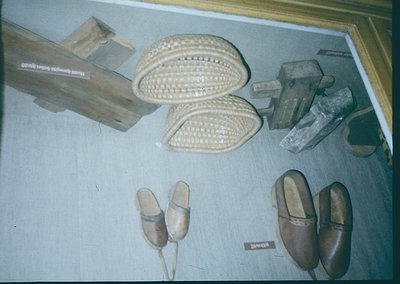 Handcrafted footwear display featuring traditional leather sandals with woven straw soles, wooden clogs, and embroidered slip...