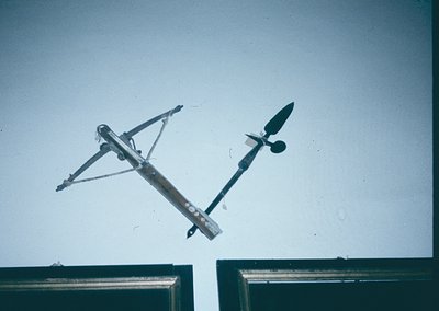 Vintage wind vane mounted on a metal frame, likely from mid-20th century industrial or agricultural site. The design features...