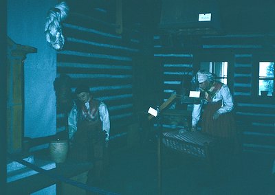 Industrial-era workshop with two workers operating vintage machinery. Dark, wood-paneled interior suggests 19th–early 20th ce...