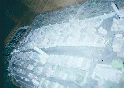 Aerial view of a coastal cityscape with dense urban layout, likely from the 1960s–1980s. Grid-pattern streets, low-rise build...