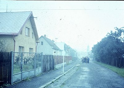 Vintage street scene featuring uniform Soviet-era apartment blocks with pitched roofs and chain-link fences. Foggy atmosphere...