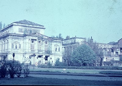 Neoclassical building with symmetrical façade, arched windows, and decorative reliefs, likely from early 20th century. Courty...