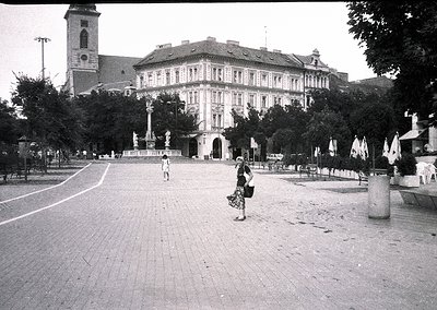 Mid-20th century urban plaza featuring a grand, symmetrical building with classical architecture—ornate façade, arched window...