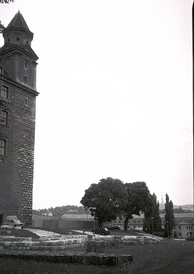 Historic stone tower with conical roof, likely part of a medieval fortress or watchtower. Surrounding ruins and low-lying bui...