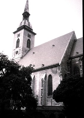 Historic church with Gothic Revival architecture—tall spire, pointed arches, and slate roof. Stone façade shows weathering, w...