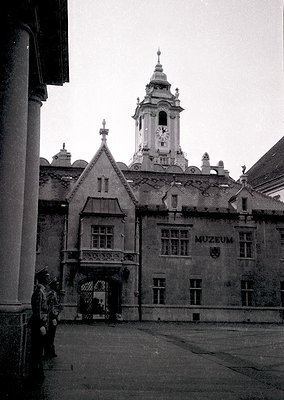 Historic courtyard entrance to a museum building with Gothic Revival architecture—steeple clock tower, arched gateway, and st...