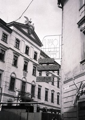 Neoclassical building corner with vintage signage: "Dieva Restauracia" (God’s Restaurant) in Cyrillic, featuring a stylized f...