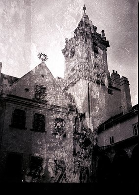 Historic European clock tower with Gothic Revival architecture, featuring a steeply pitched roof and ornate stonework. Adjace...