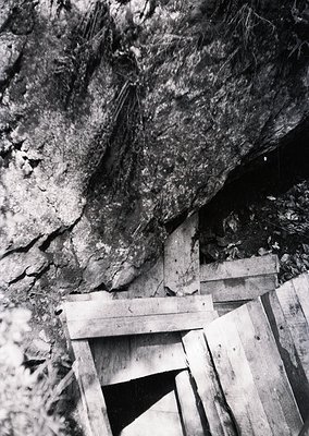 Industrial-era wooden support beams and rock face in a mine shaft, likely coal or ore extraction. Rustic timber framing stabi...