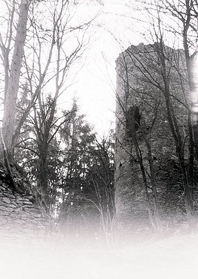 Vintage sepia-toned photograph of a mist-shrouded stone tower flanked by leafless trees, suggesting winter or early spring. T...