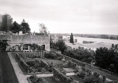 Historic estate garden with formal raised beds, stone walls, and a river valley beyond. Likely late 19th to early 20th centur...