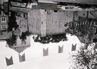 Aerial view of a courtyard with mirrored water reflecting historic European architecture, likely 1960s–1970s. Symmetrical bui...
