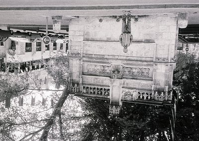 Aerial view of a grand, decaying neoclassical building façade with ornate balustrades and sculptural reliefs, likely from the...
