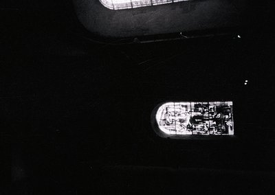 Aerial view of a small, dark-toned vessel with visible deck structures and a single mast, likely a sailboat or small yacht. T...
