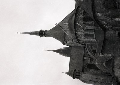 Aerial black-and-white photograph of a medieval fortress with steep, conical towers and crenellated walls, likely from the 12...