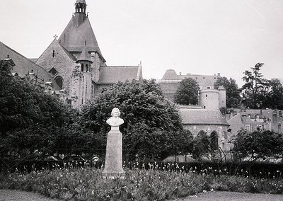 Historic black-and-white photo of a European castle courtyard with Gothic Revival architecture—steepled towers, crenellated w...