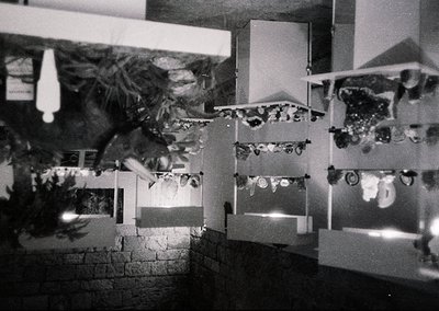 Black-and-white interior shot of a gallery or exhibition space featuring abstract geometric artworks. Framed pieces arranged ...