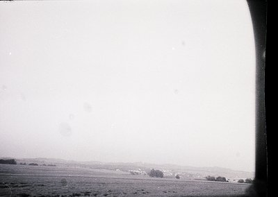 Vintage black-and-white aerial view of flat, open terrain with sparse vegetation and faintly visible tree clusters. Likely ca...