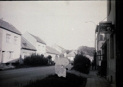 Vintage black-and-white street scene featuring a hand-painted protest sign in Cyrillic script, likely Bulgarian, with a "Denn...