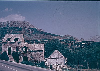 Vintage stone farmhouse cluster nestled in a Mediterranean hillside landscape, likely -70s. Rustic architecture with flat roo...