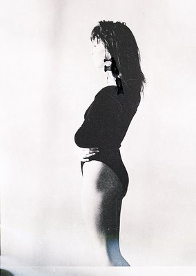 Silhouetted figure in a sleek, form-fitting black swimsuit, backlit against a plain background. High-waisted cut with long sl...