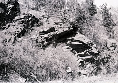Black-and-white landscape featuring layered sedimentary rock formations with visible horizontal strata, likely limestone or s...